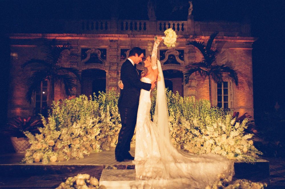 A candle-lit evening wedding reception with a couple dancing surrounded by elegant floral arrangements.