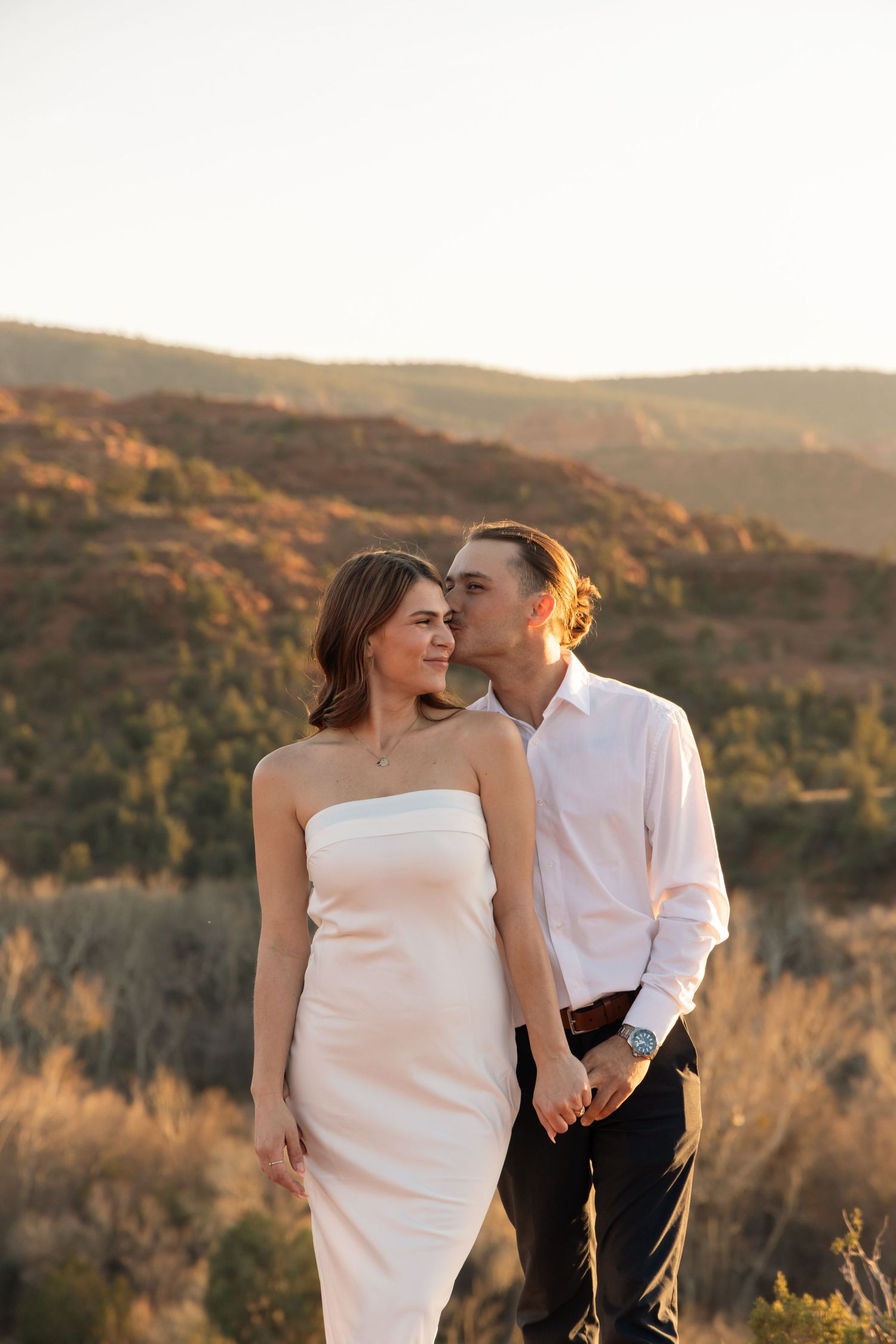 A romantic couple shares an intimate moment against a golden sunset in the mountains during their engagement photoshoot.