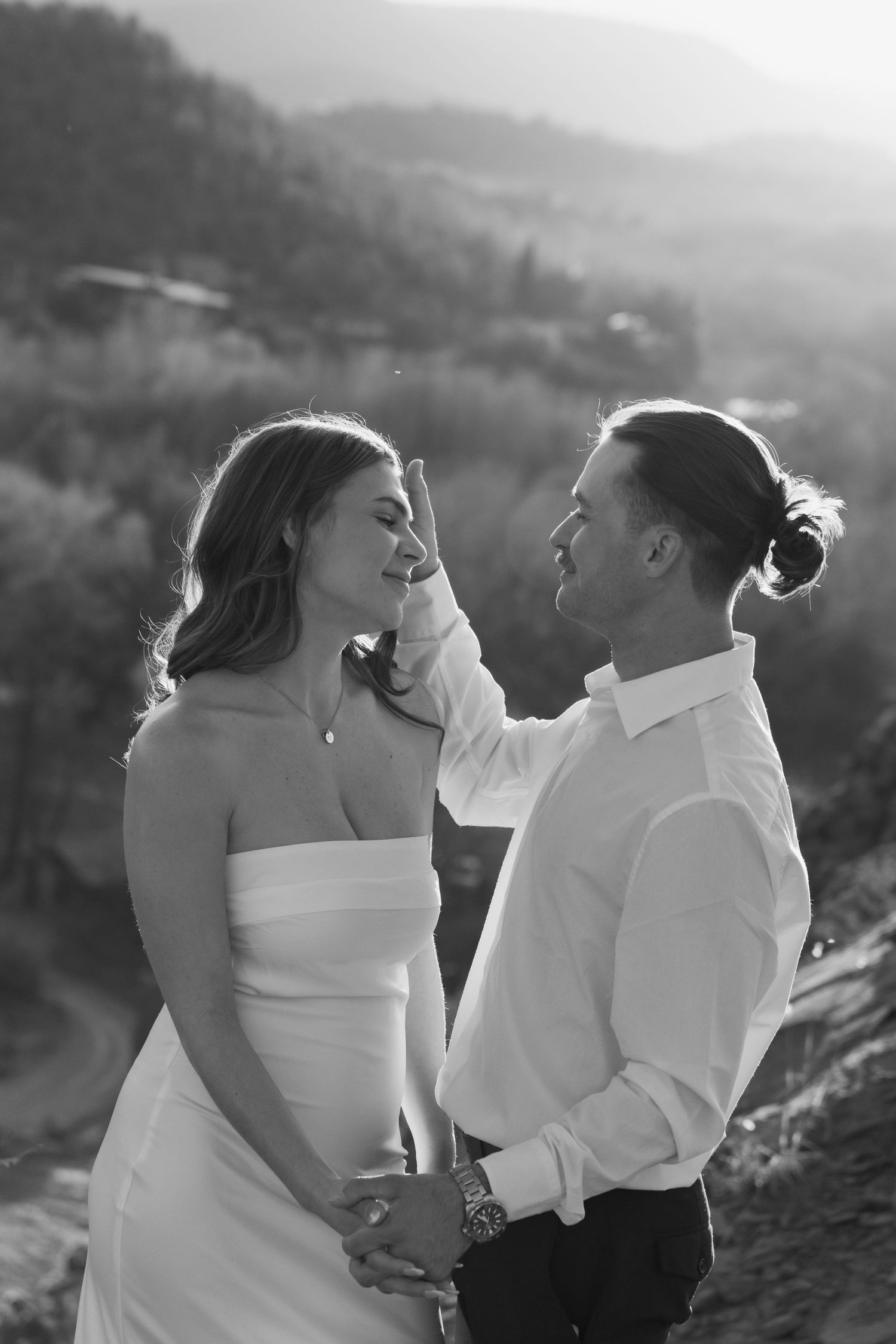 A romantic black and white photo sequence of a couple in white attire sharing intimate moments on a hillside.