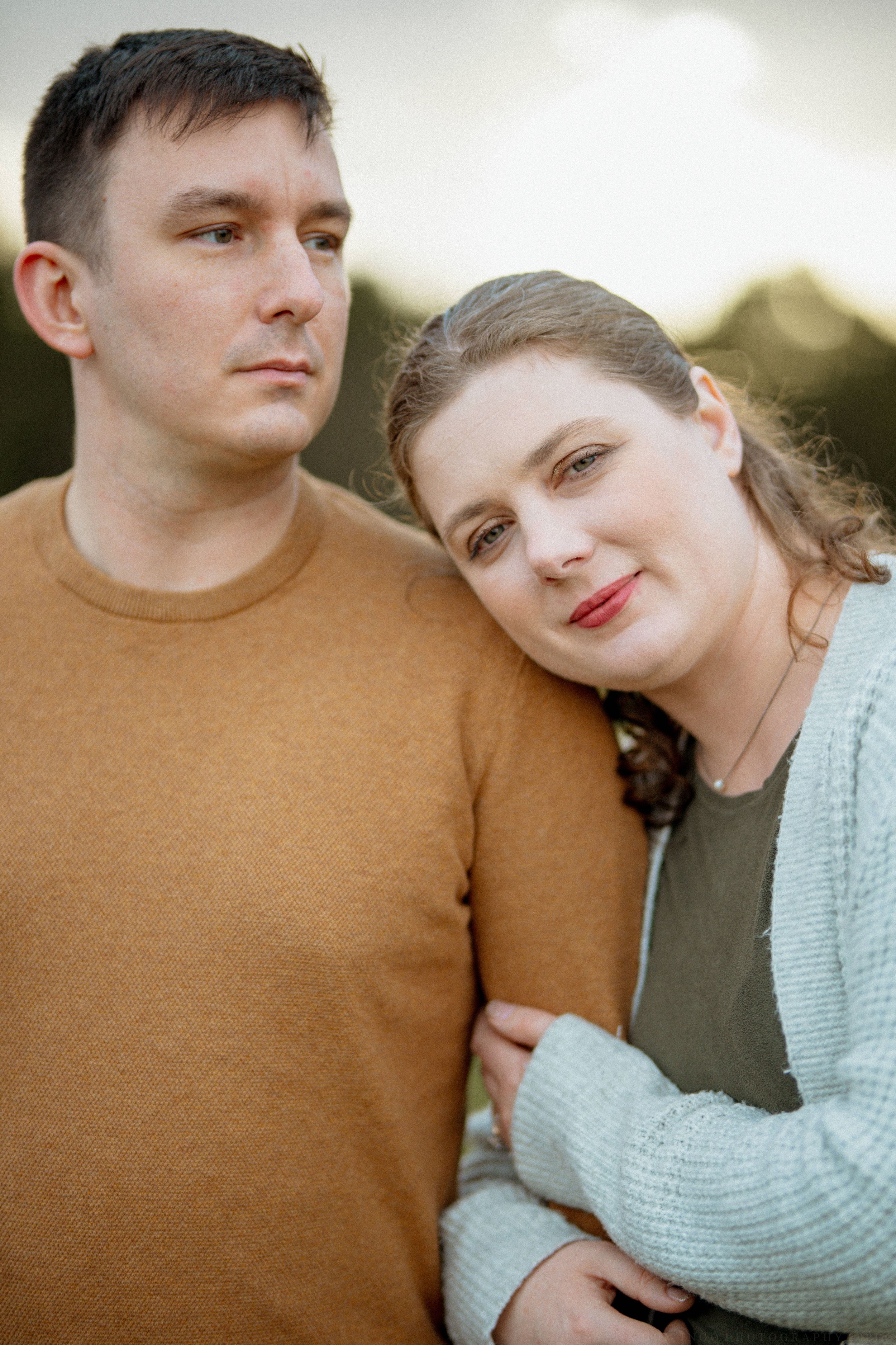 A romantic outdoor photo series of a couple embracing in warm sunlight while wearing casual sweaters.