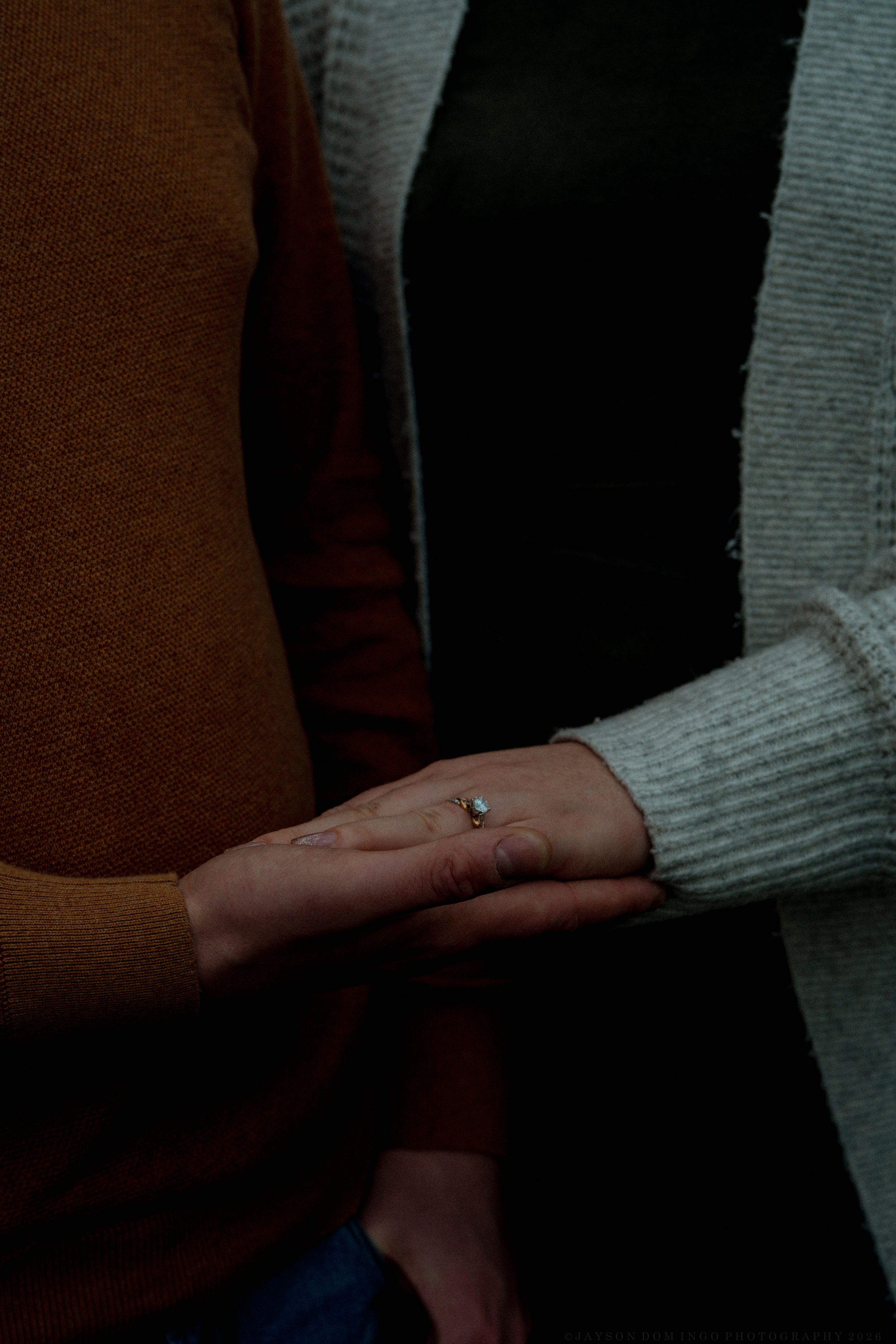 Close up shot of hands tenderly touching in soft dramatic lighting.