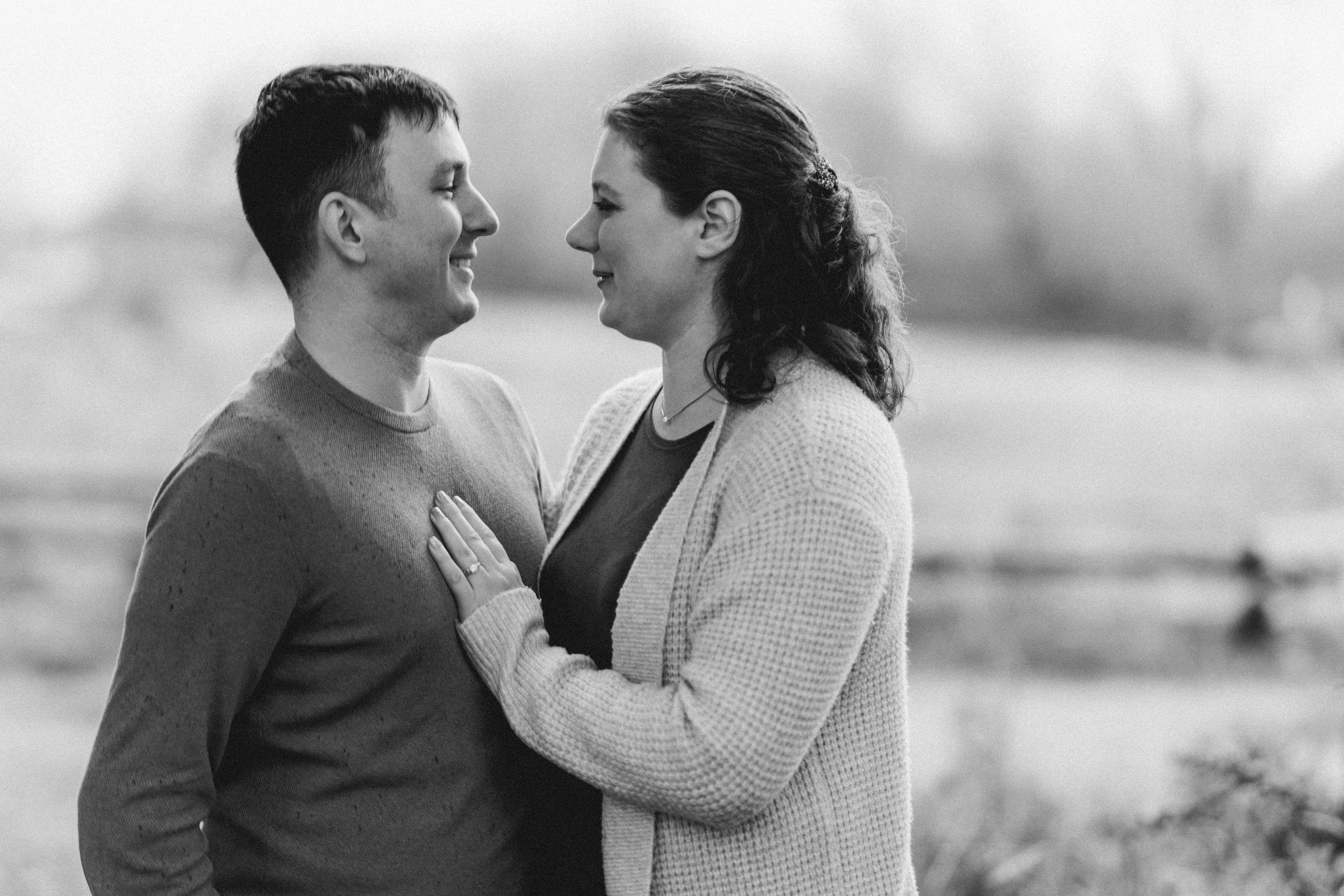 A romantic black and white engagement photo series showing tender moments between a couple in an outdoor setting.
