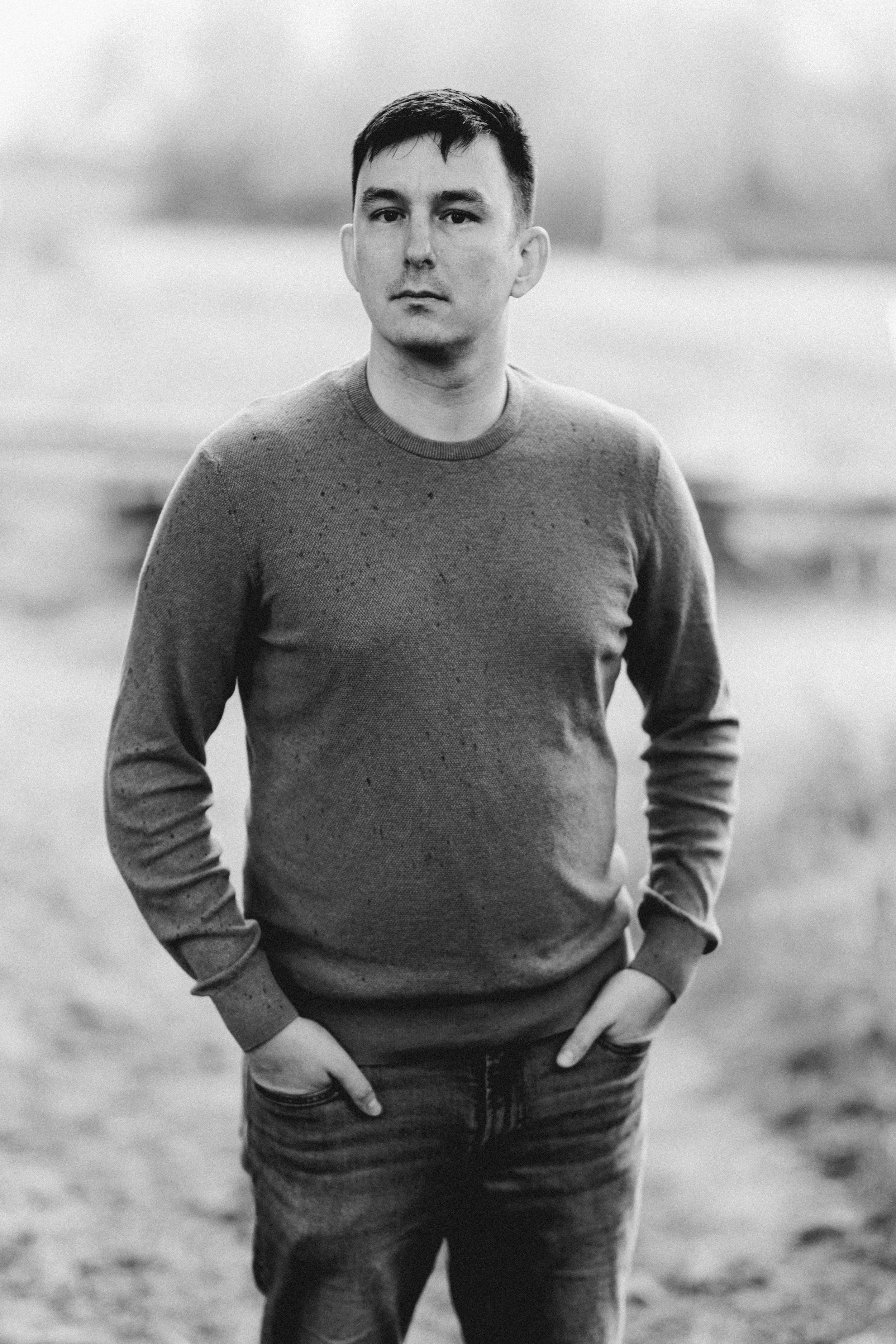 Black and white photo series showing a person in a dark sweater and pants standing in different poses outdoors.