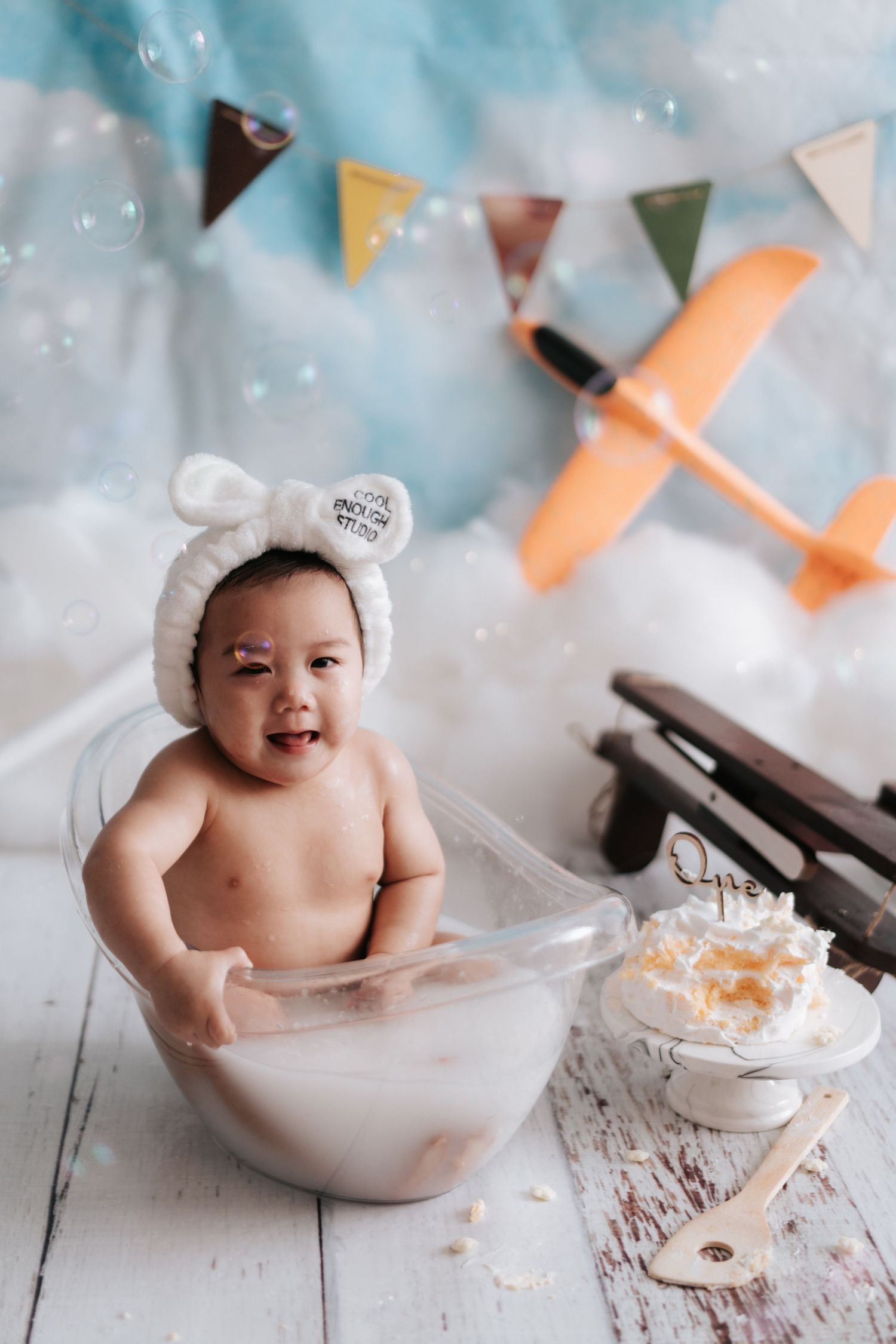 A series of bath time photos showing a baby in a white tub with bunting flags and playful splashing moments.