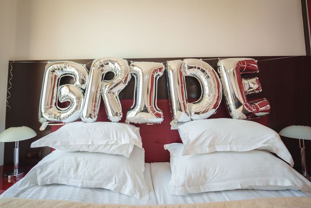 Cozy bedroom interior with white bedding and burgundy accent wall showcasing modern decor and lighting.