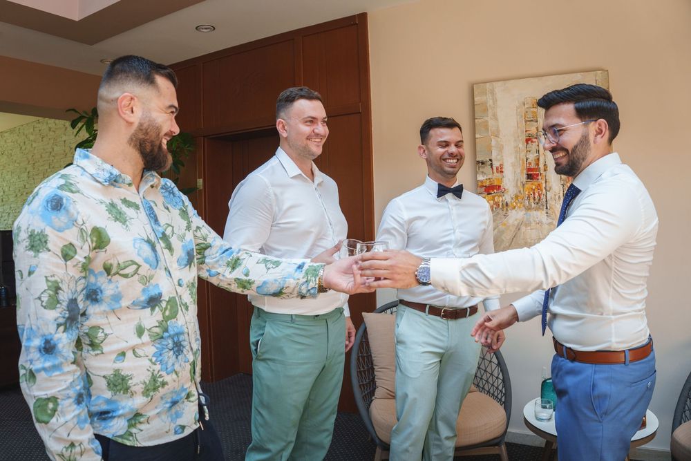 People in formal attire getting ready for an event, with one person wearing a floral patterned shirt.