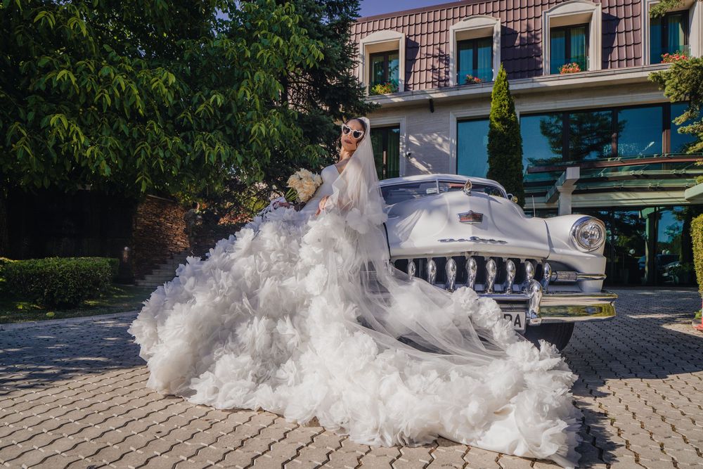 A bride in a flowing white dress twirls on a cobblestone path, creating a dramatic swirling effect with the fabric.