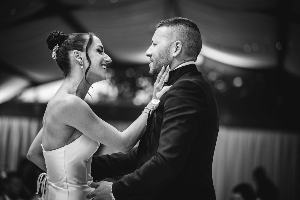 A couple dancing together in an elegant ballroom setting captured in black and white photography.