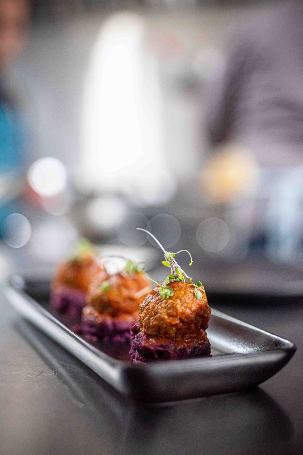 Sequence of five close-up shots showing a small appetizer dish on a black plate with garnish and sauce.