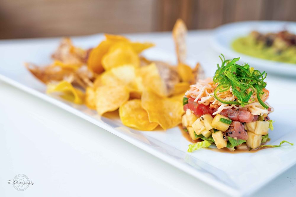Elegant plated appetizers featuring fresh seafood and colorful garnishes served on white rectangular dishes.