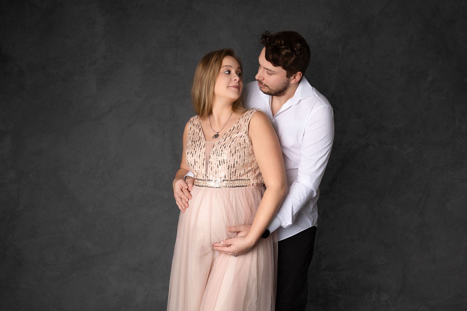 A romantic couple in elegant attire shares intimate moments in a series of black and white studio photographs.