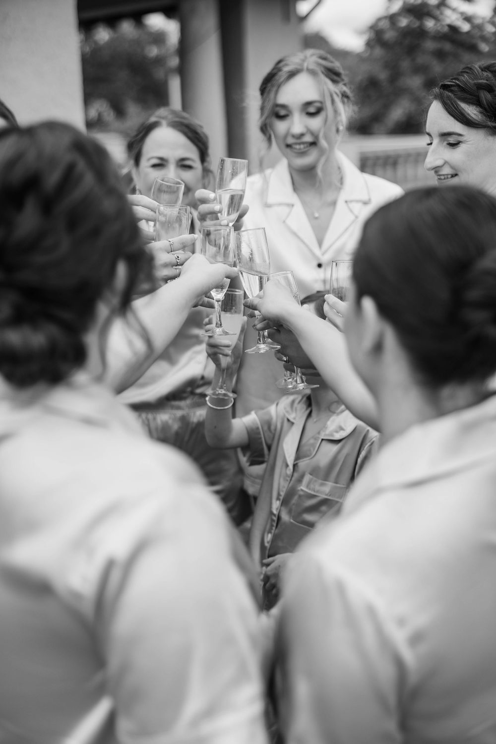 Wedding guests raise champagne glasses in a celebratory toast during an outdoor reception.