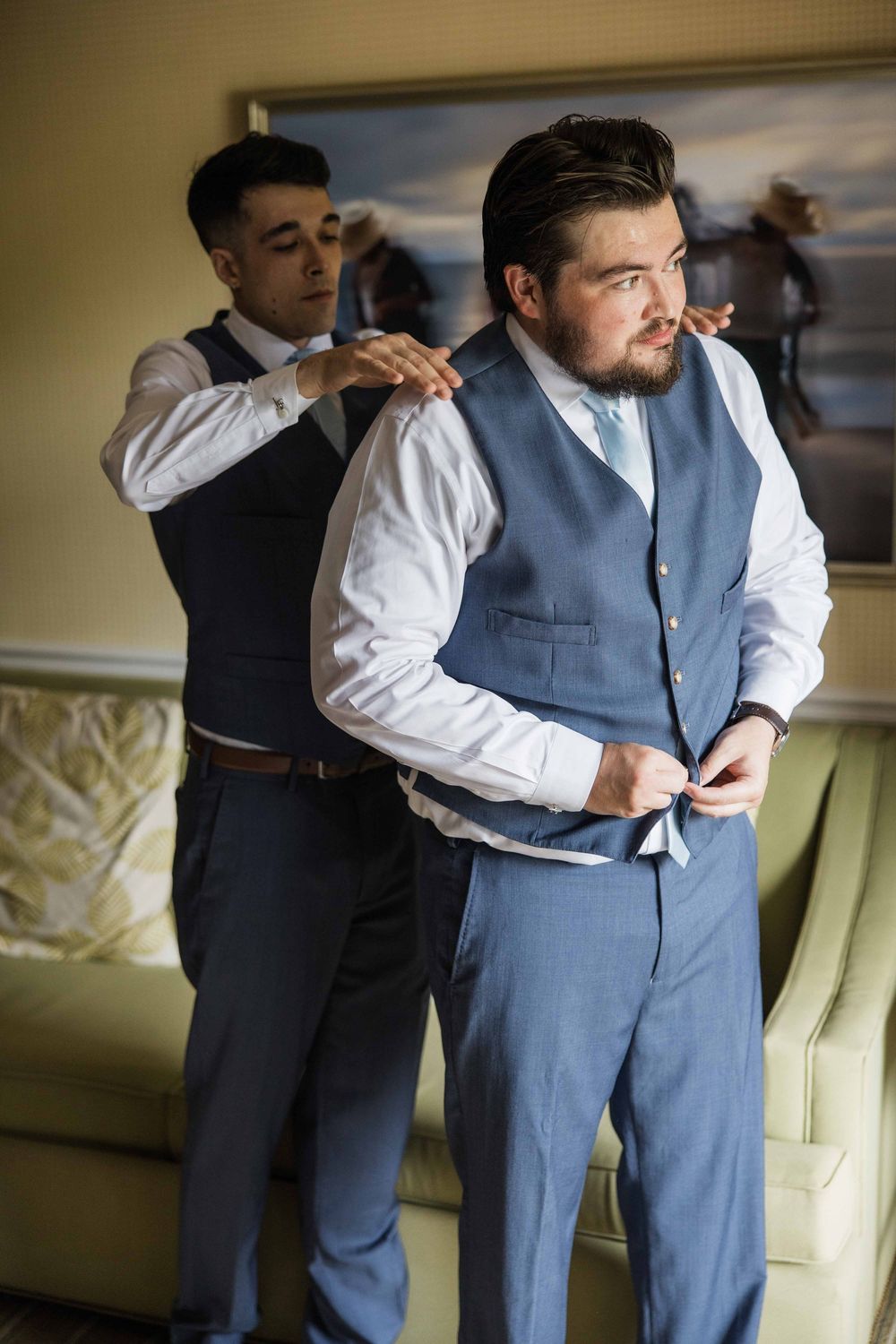 A series of photos showing groomsmen helping adjust a light blue vest and formal attire before a wedding.