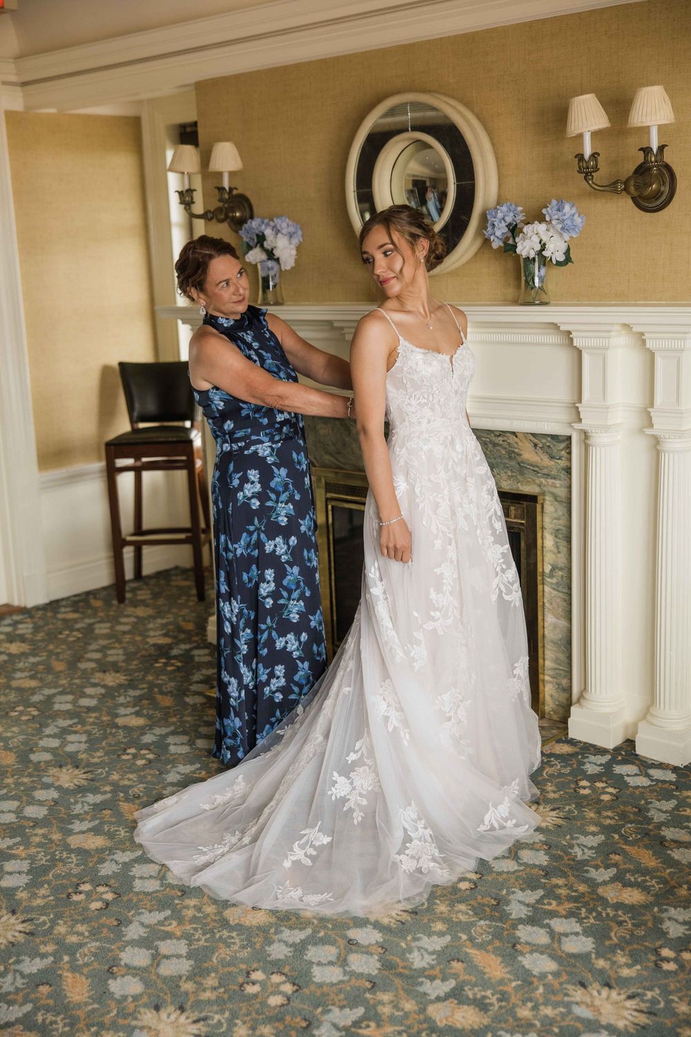 A sequence showing final wedding dress adjustments being made in an elegant room with floral carpeting.