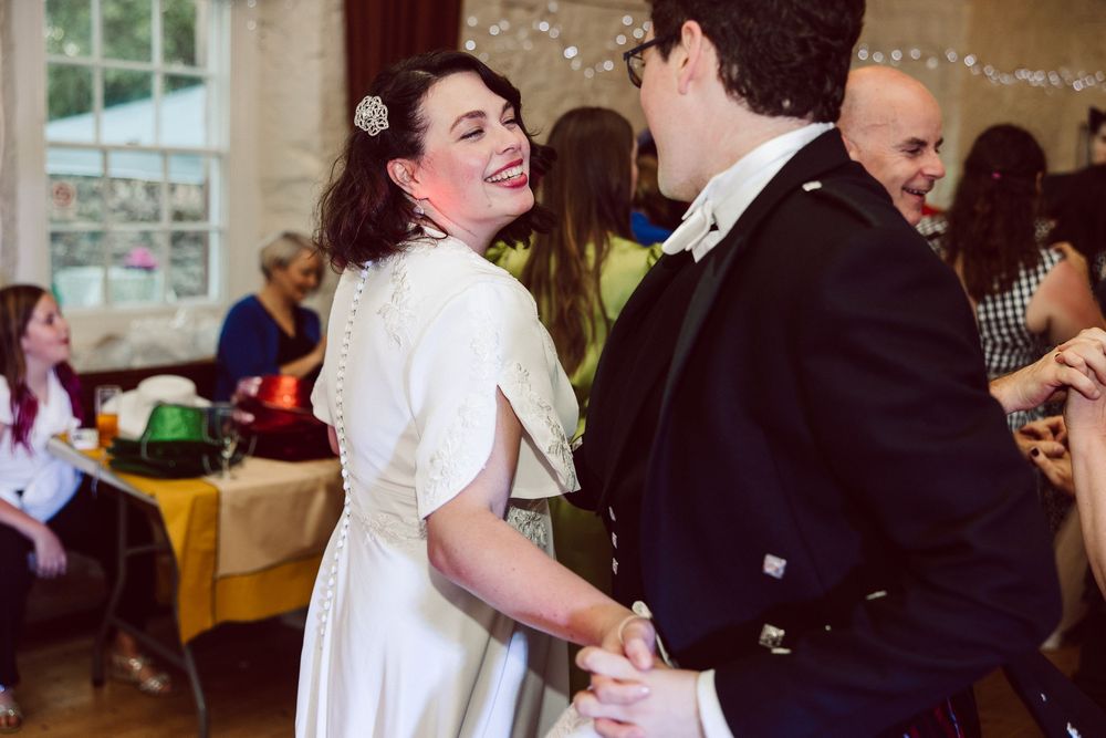Newlyweds share their first dance together under twinkling lights at an elegant indoor wedding reception.