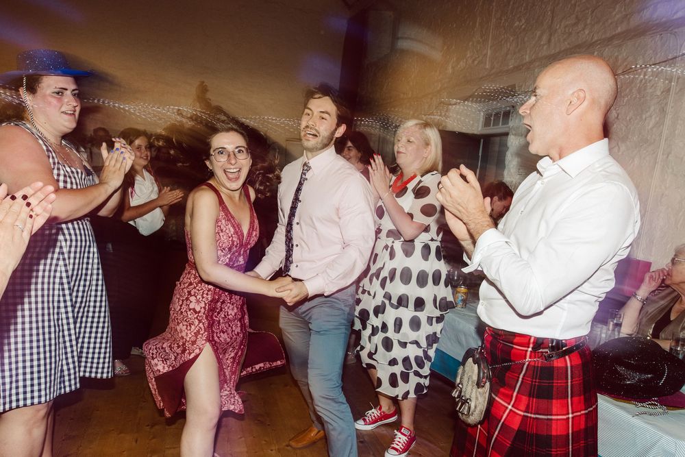 People dancing together at a wedding reception with warm lighting and festive atmosphere.