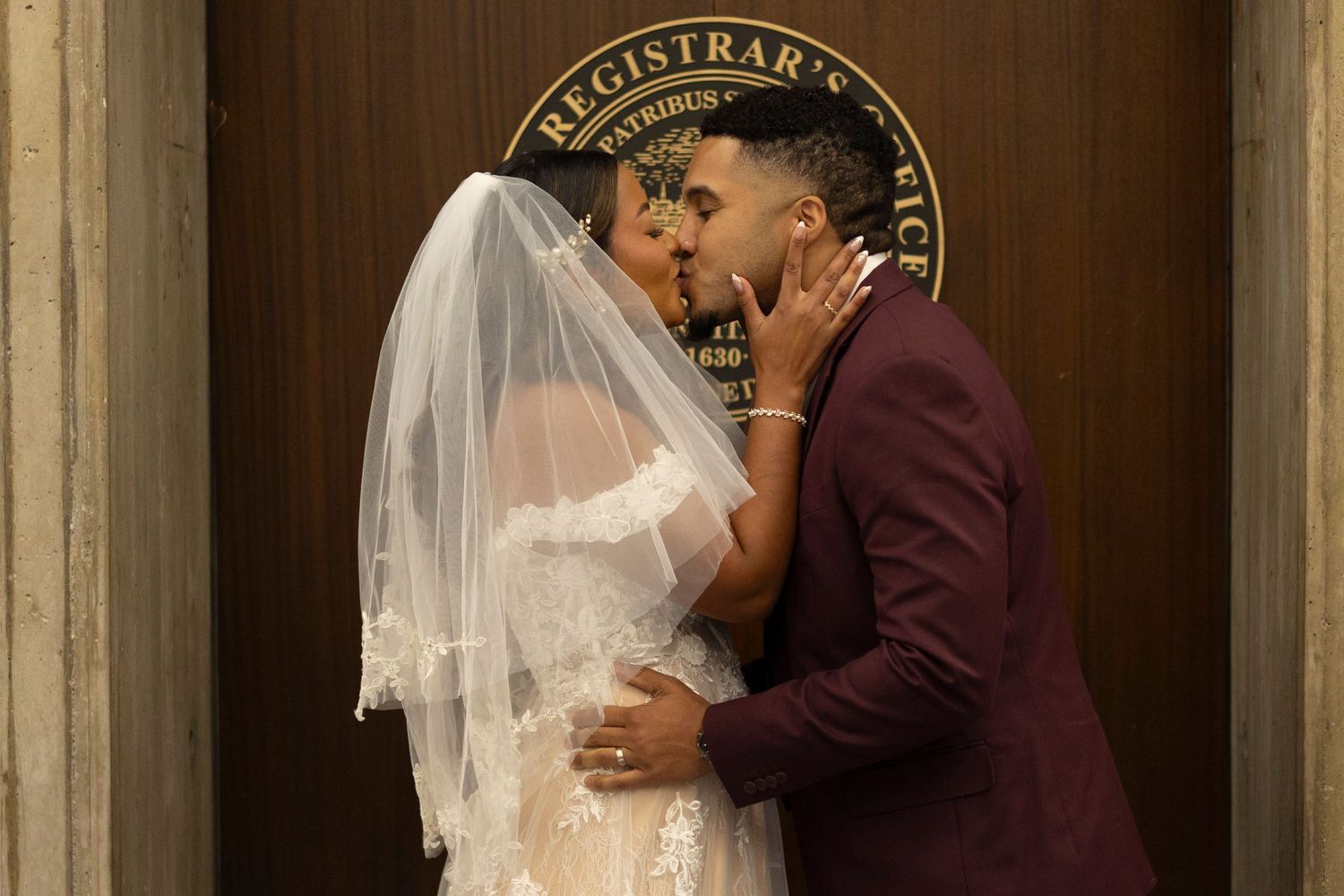 A couple in wedding attire embraces during their marriage ceremony at a courthouse.