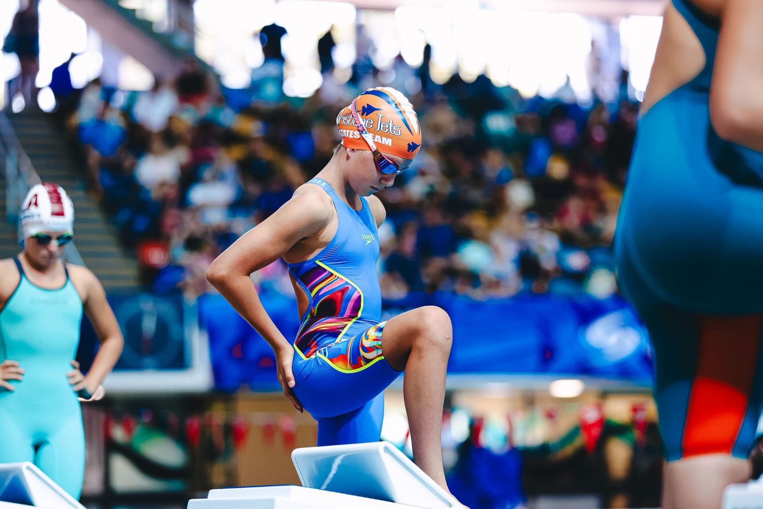 Swimmers diving off starting blocks at a competitive swimming event in a professional pool setting.