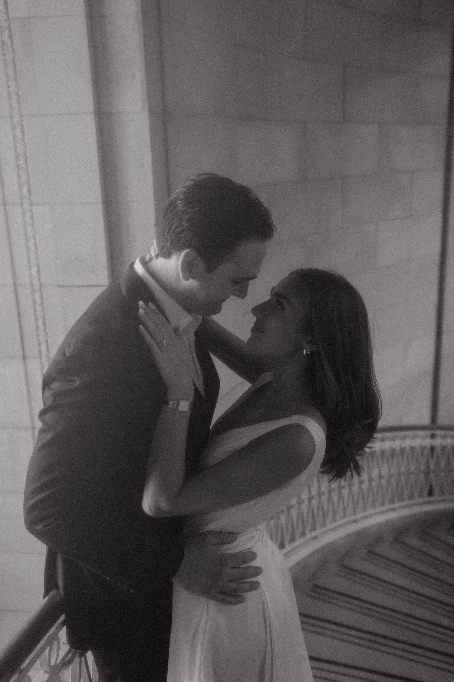 A romantic black and white photo series showing a couple embracing and kissing in an elegant architectural setting.