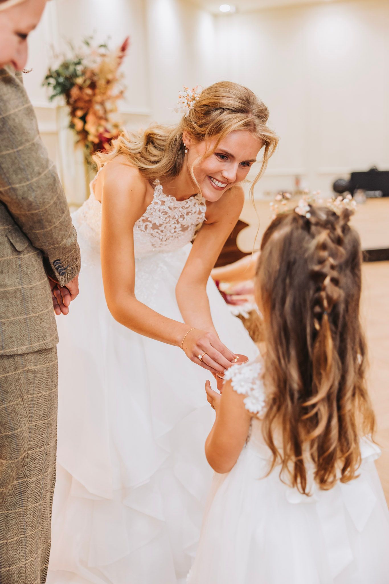 A touching moment between a bride in a white lace dress and a young flower girl at a wedding ceremony in indoor venue BLOQ23, Hoofddorp