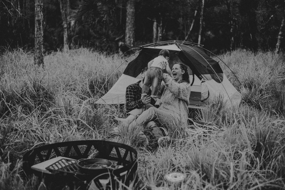 Family relaxes together on a blanket in a grassy field during an autumn outdoor photoshoot.