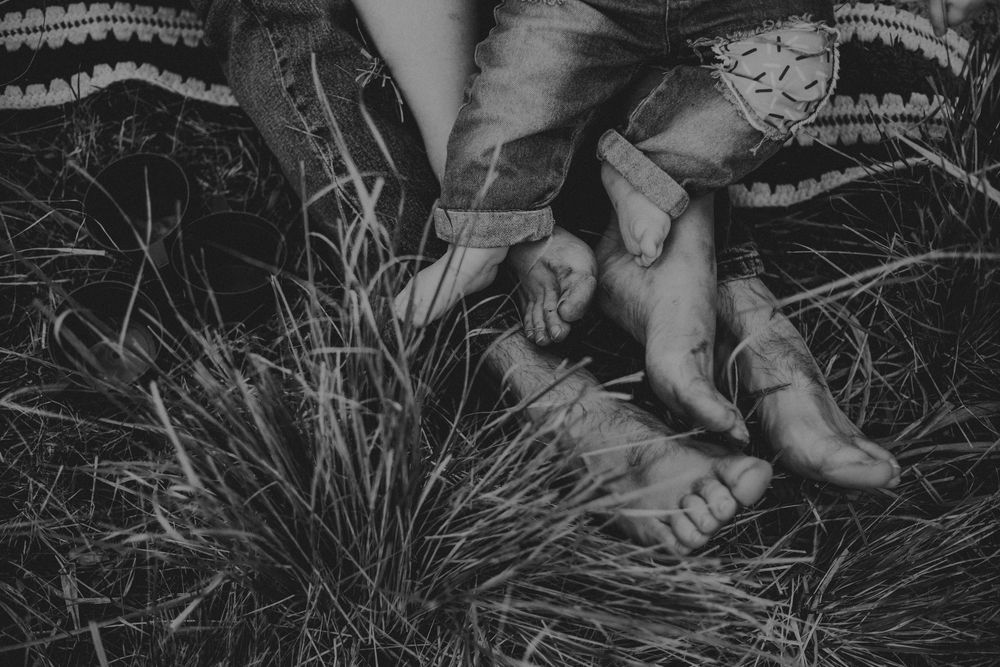 A couple relaxes in a field of dried grass during an intimate outdoor photo session.