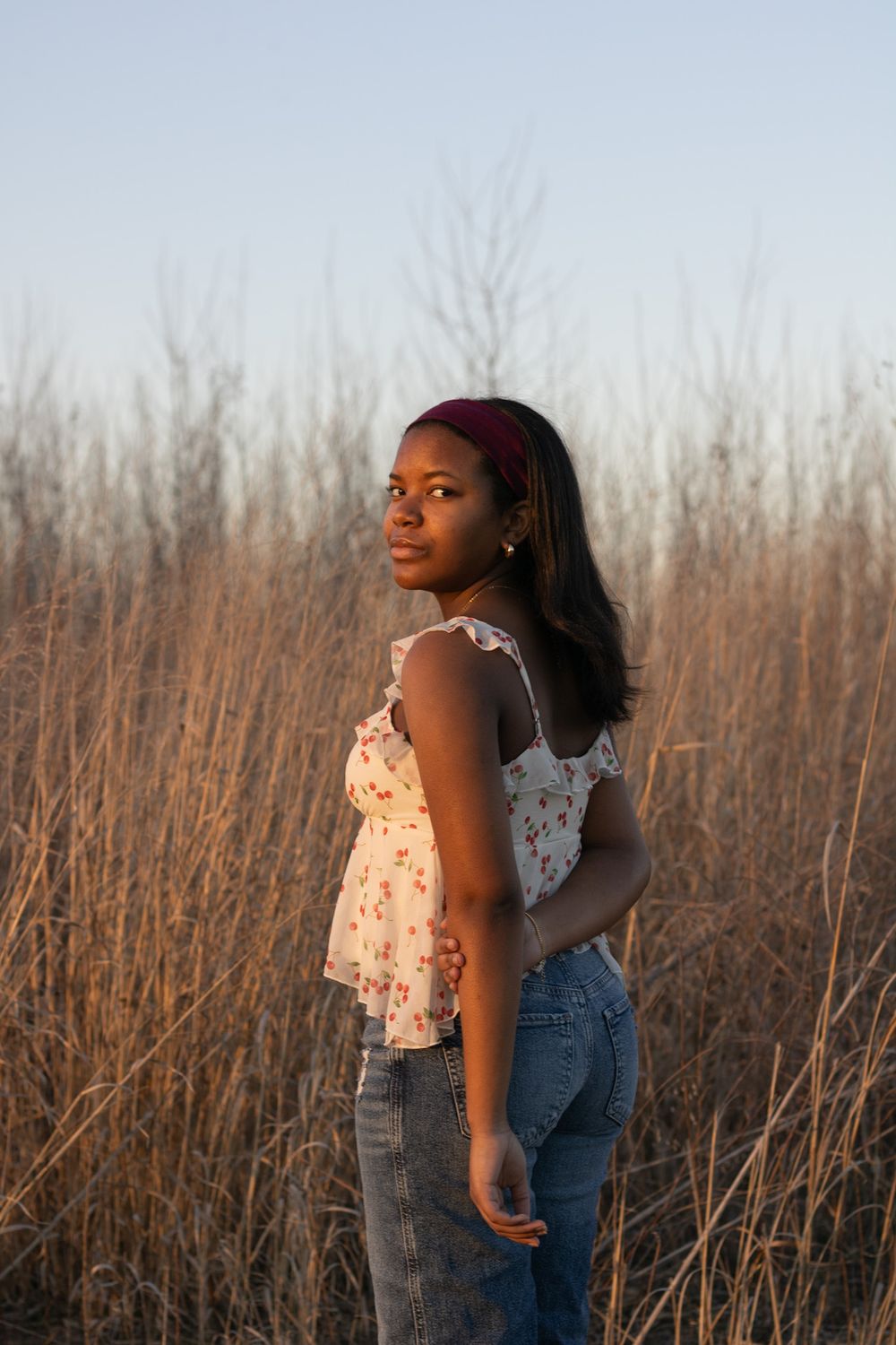 A portrait against dried grass and bare trees at golden hour.