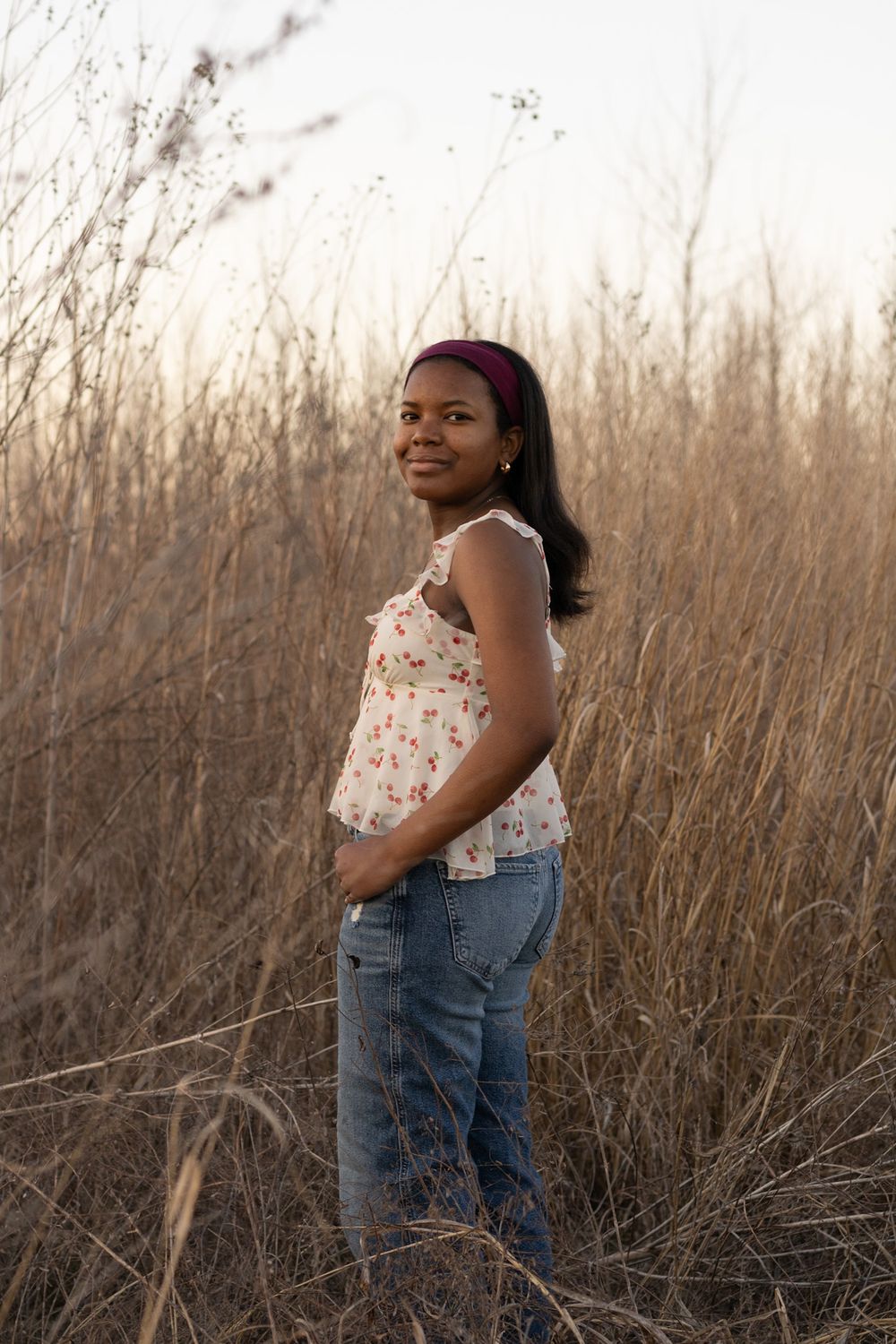 A casual outdoor portrait in a field of tall dried grass during sunset.