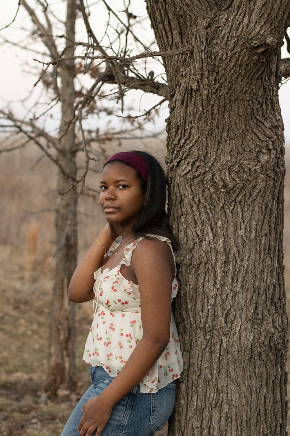 Natural portrait against a tree trunk in casual autumn attire.
