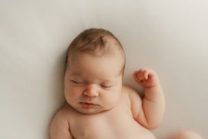 Peaceful sleeping newborn baby with soft skin against white background.