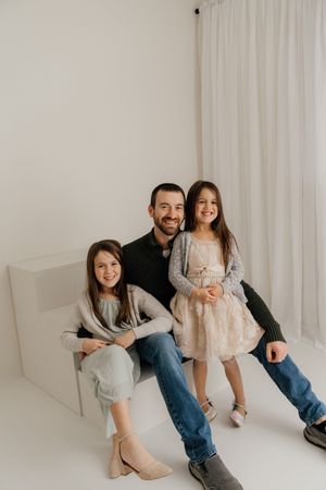 A family poses together in a minimalist white studio setting wearing casual clothing and boots.