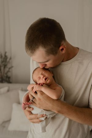 Intimate portrait of parent tenderly holding sleeping newborn baby.