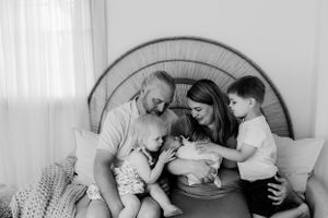 A loving family scene in black and white with parents and children gathered together on a couch.