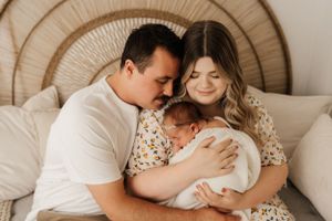 Intimate family moment on bed with woven headboard.