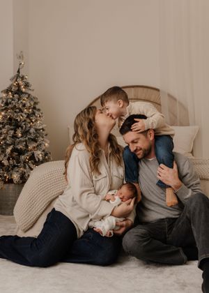 A loving family shares tender moments together by their decorated Christmas tree in a cozy living room setting.