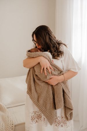 A series of warm-toned photos showing someone wrapped in a cozy beige sherpa blanket against a light background.