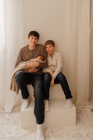 Two people sit casually on white window ledges in a minimalist room with white carpeting and walls.