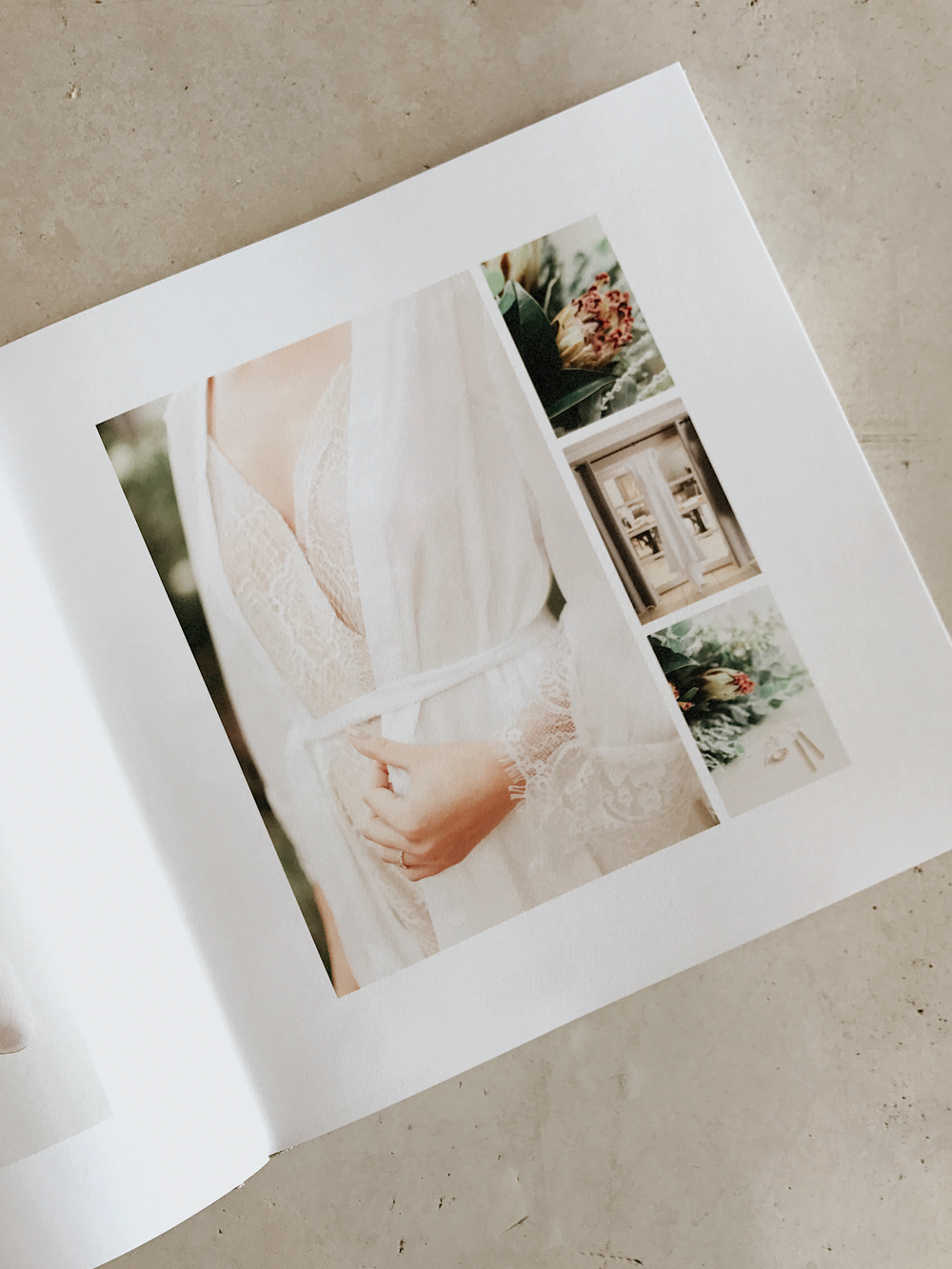 Open wedding photo album displaying elegant bridal portraits including bride in lace gown holding flowers on white pages.