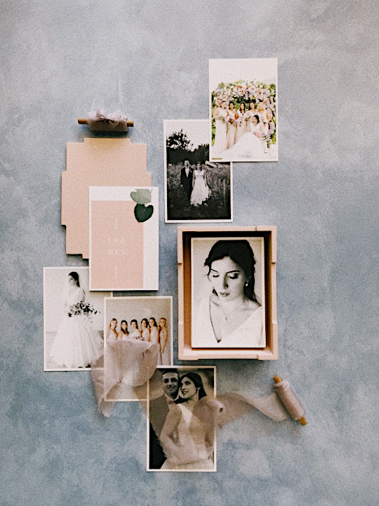Flat lay collection of wedding photos including bride, bridesmaids, and couple portraits arranged on blue-gray surface.