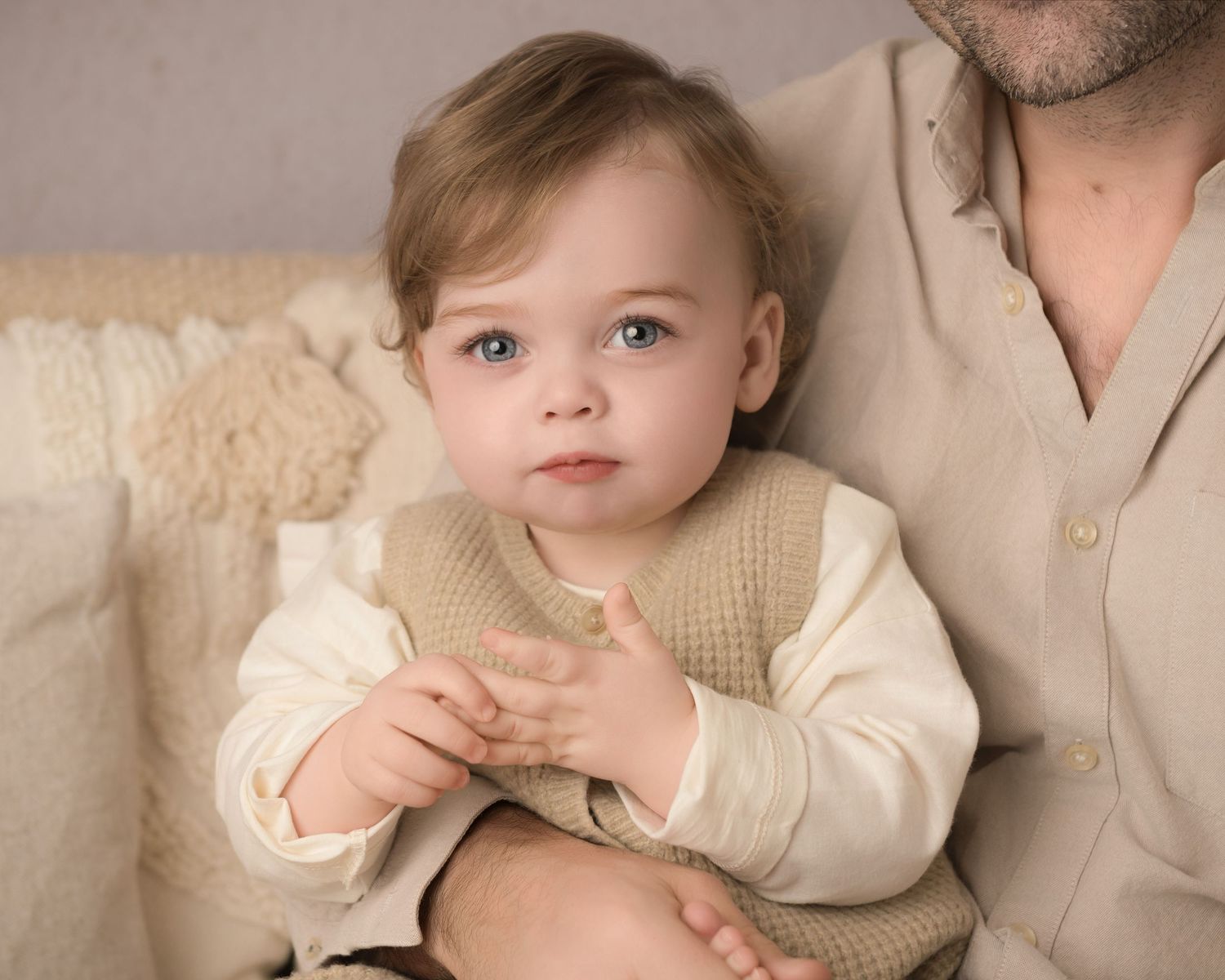 A family wearing neutral cream colored outfits poses together for a soft, minimalist portrait session.