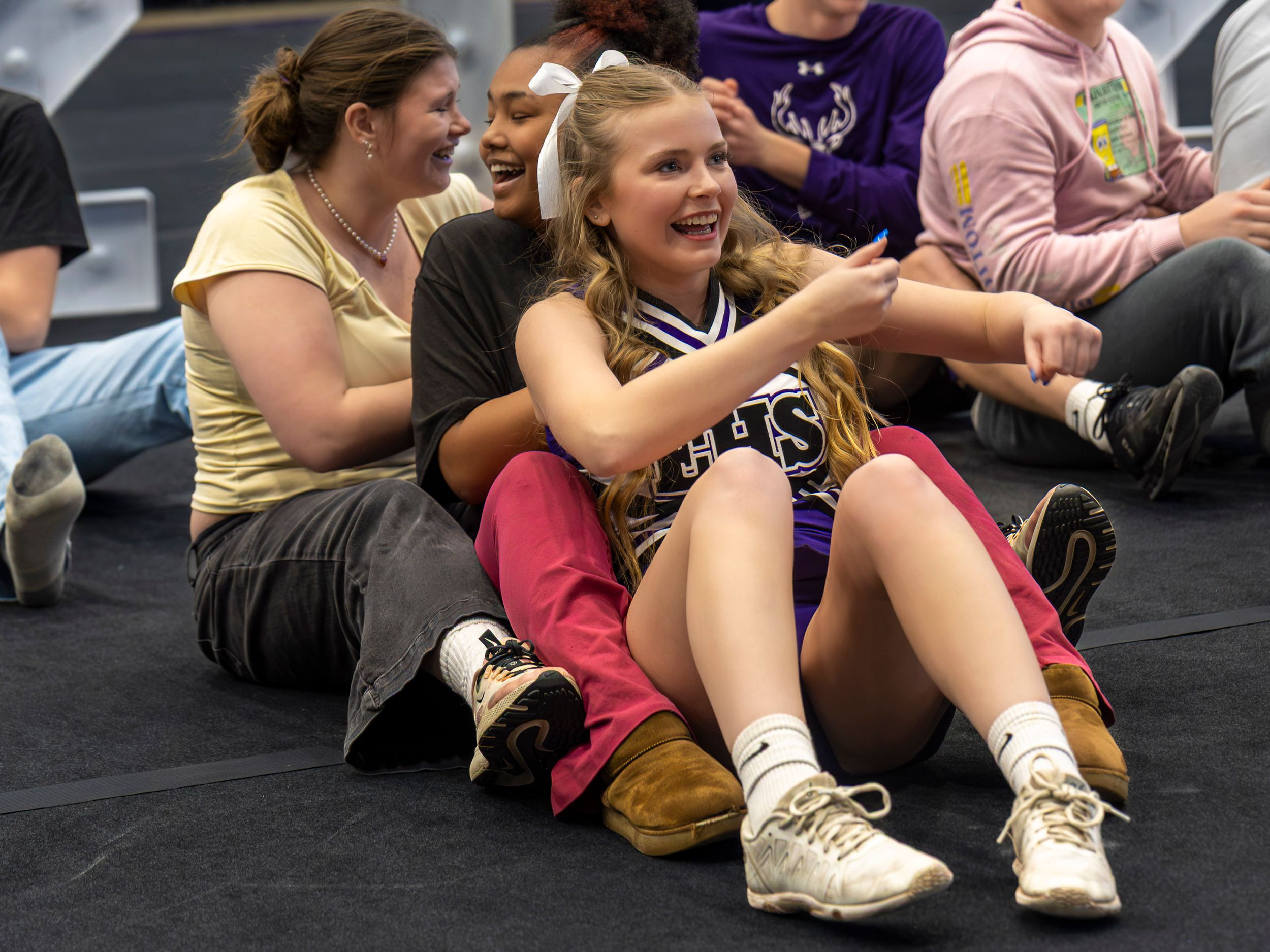 Group of people sitting on a gym floor during a fitness class or workout session.