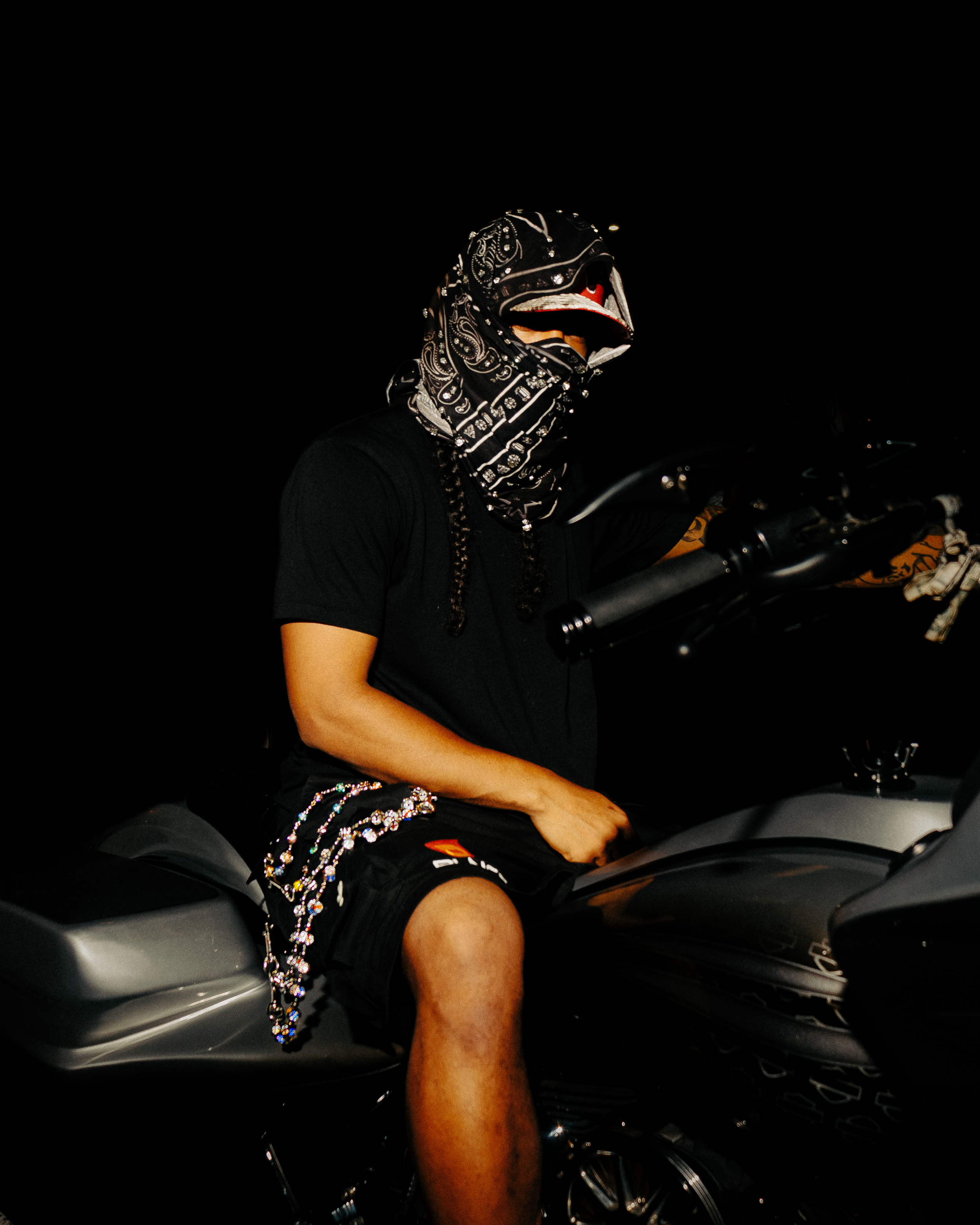 A motorcycle seat and body panel shown in dramatic low-light conditions with partial illumination.