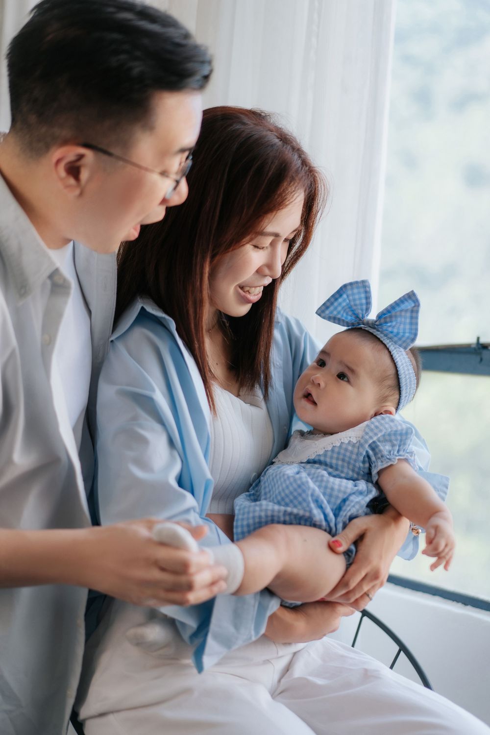 A tender family moment captured in a series of candid photos showing parents bonding with their baby by the window.