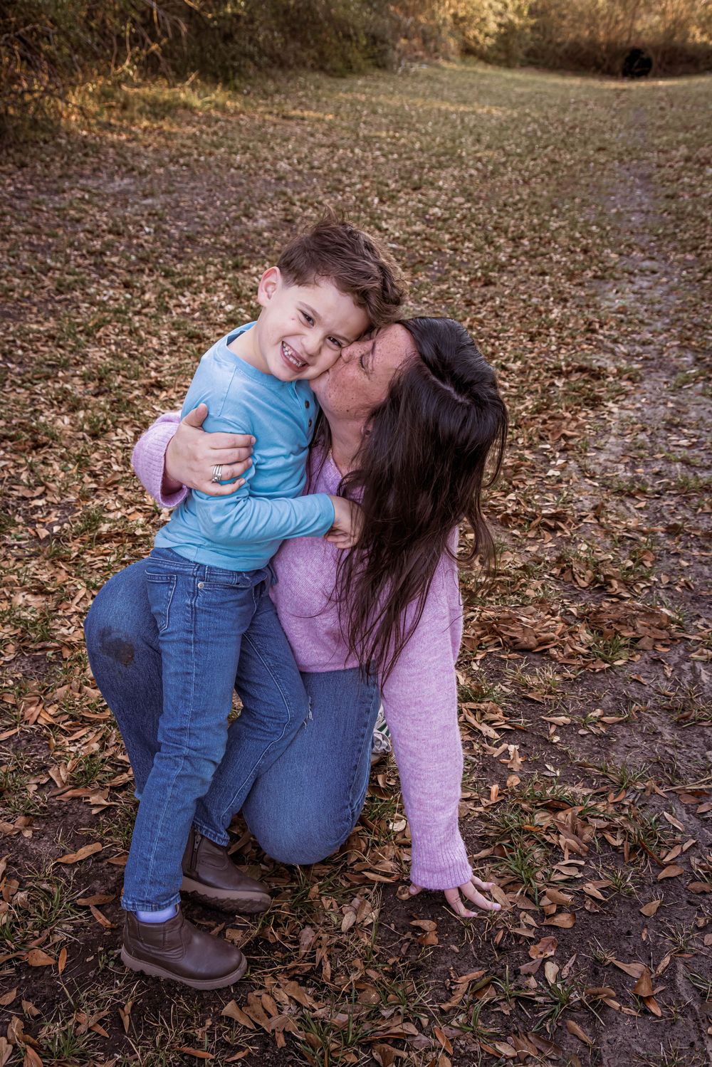 Sweet candid moments captured on fallen autumn leaves between two people sharing affectionate embraces.