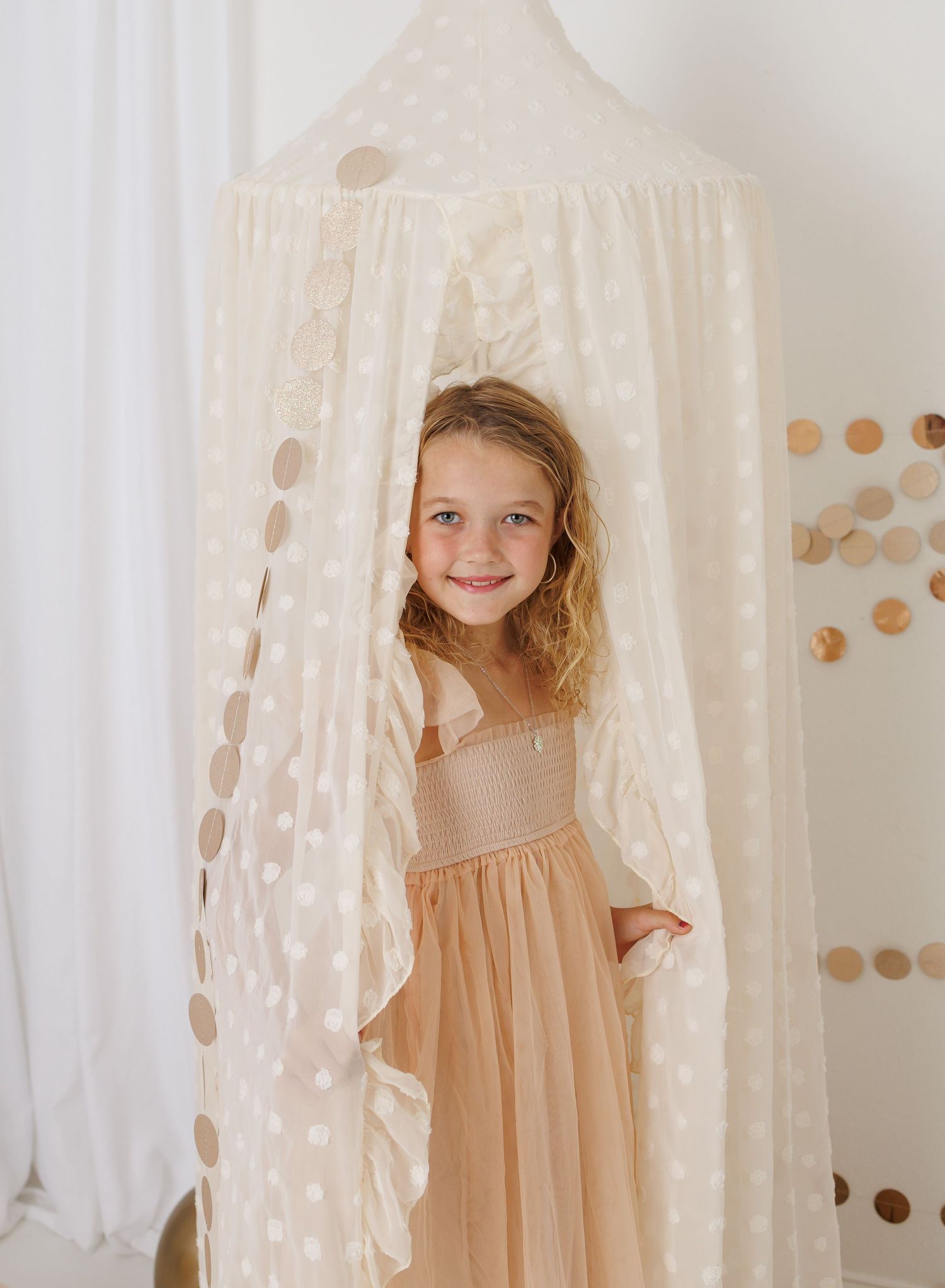 A person in a pink dress lies dreamily in a bathtub filled with milk and floating glitter creating a magical atmosphere.