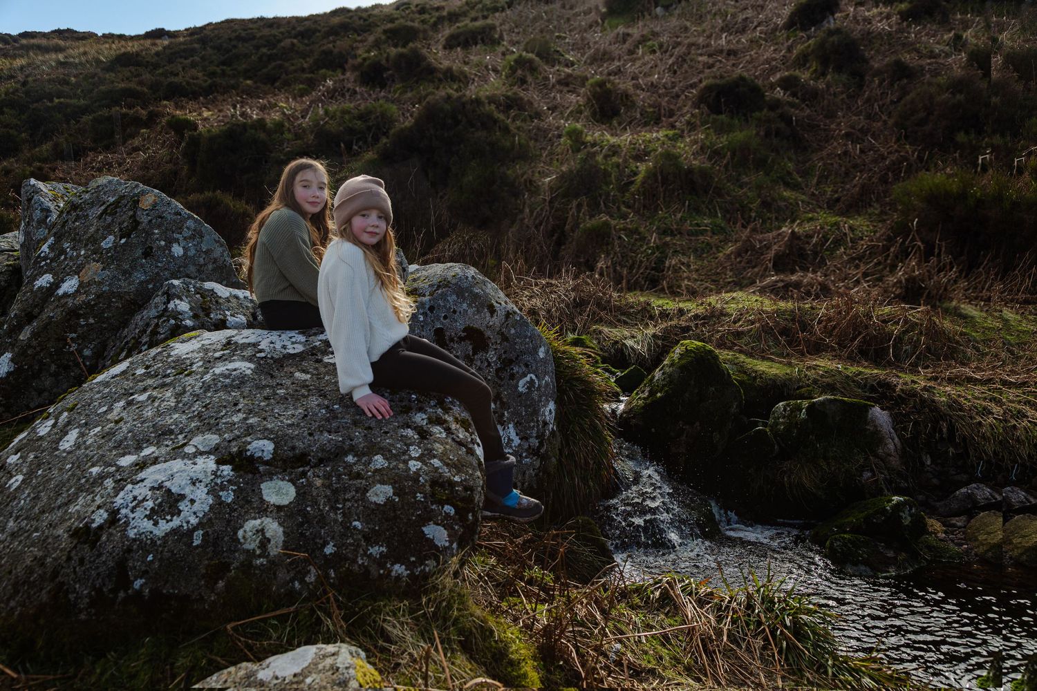A portrait photo of two girls sitting on rocky outcrops during their wicklow tour.