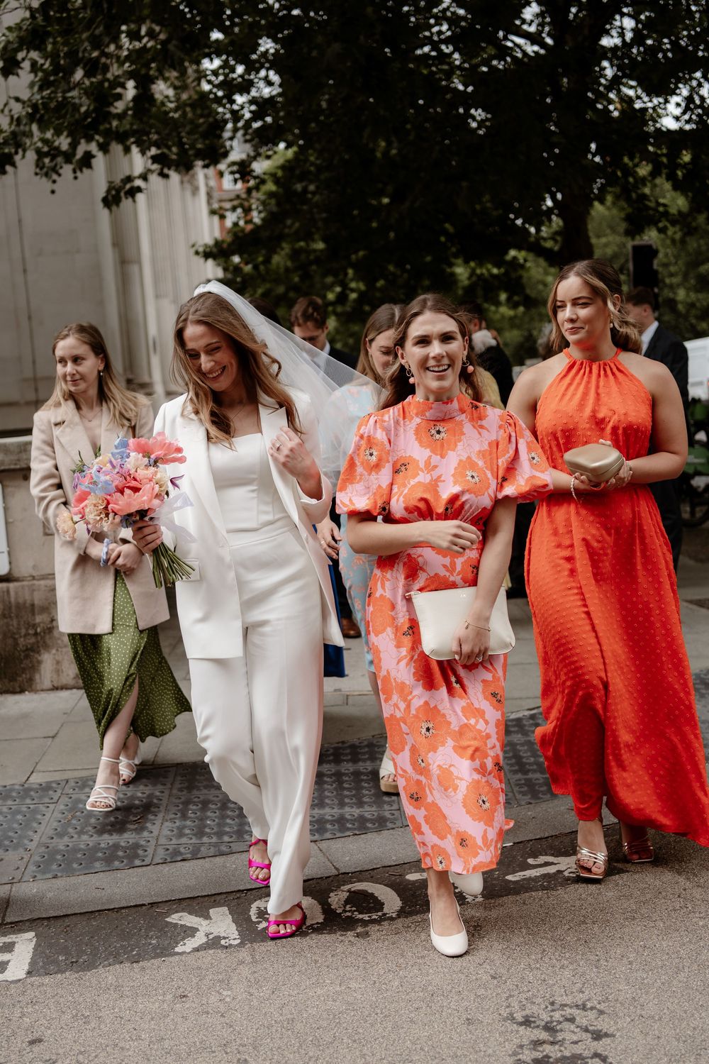 A series of wedding party photos showing bridesmaids in orange and coral dresses walking and posing together outdoors.