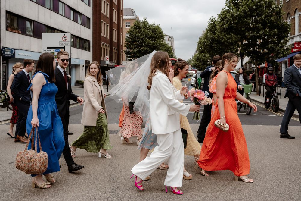 Wedding guests dance and celebrate during a joyful outdoor reception on a sunny day.