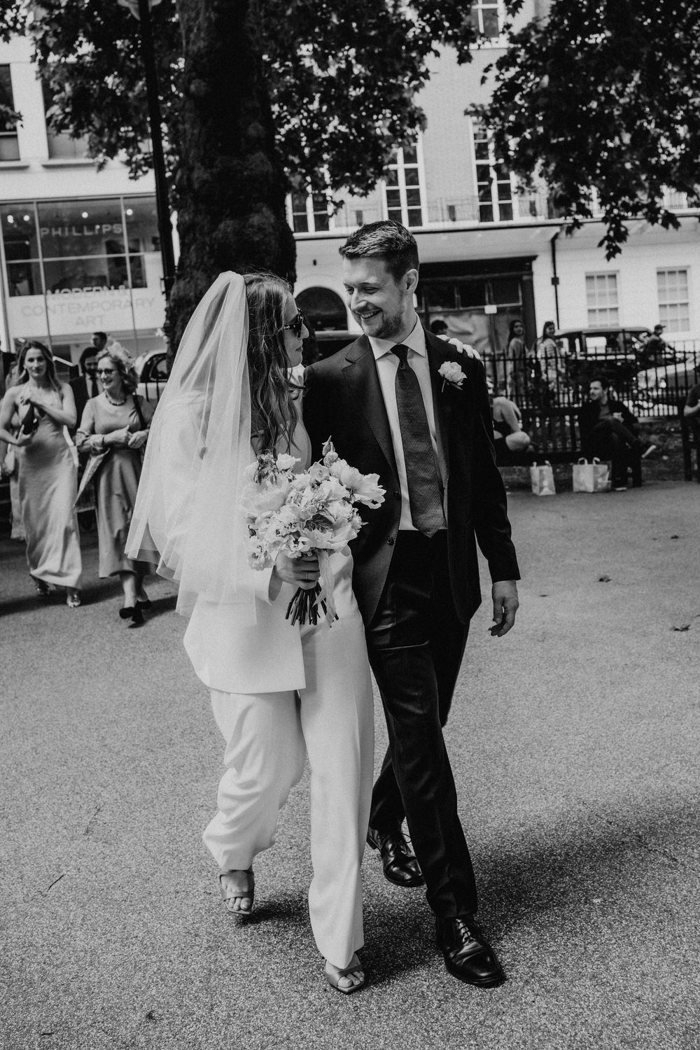 Black and white wedding photo series showing a couple walking and laughing together outdoors.