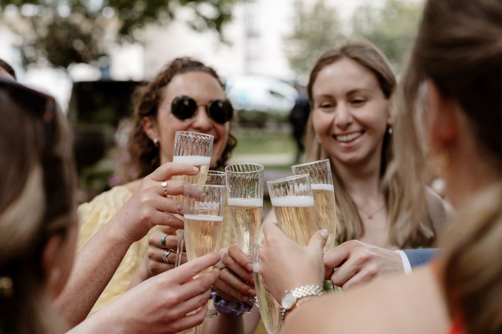 People raising glasses in a celebratory toast at an outdoor gathering.